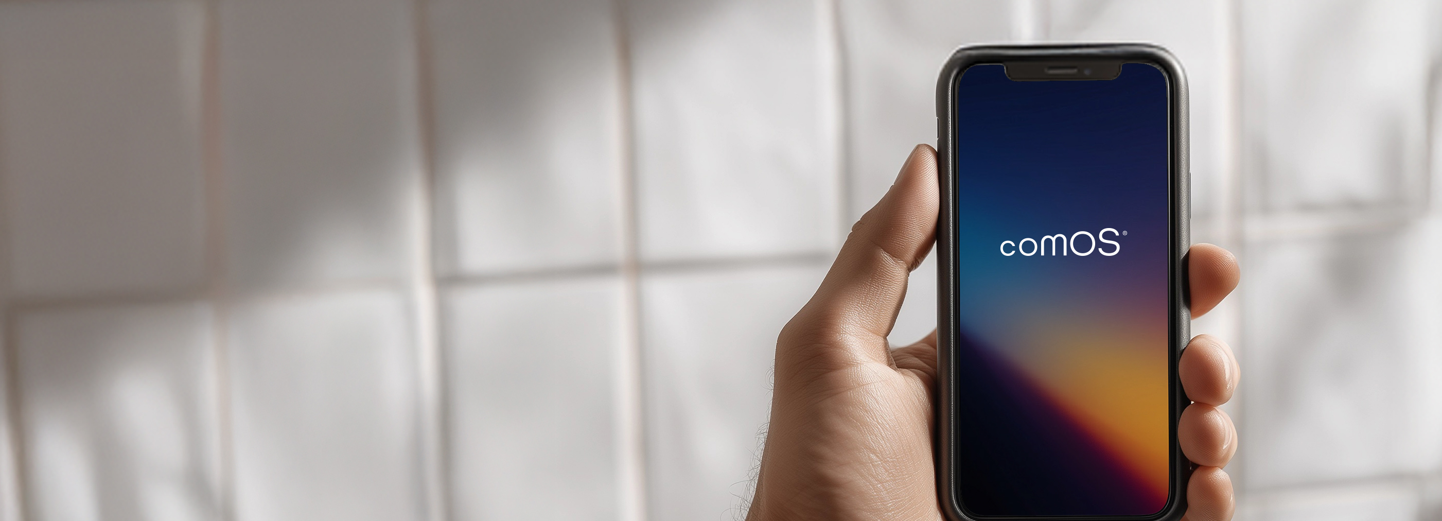 Hand holding smartphone with comOS app